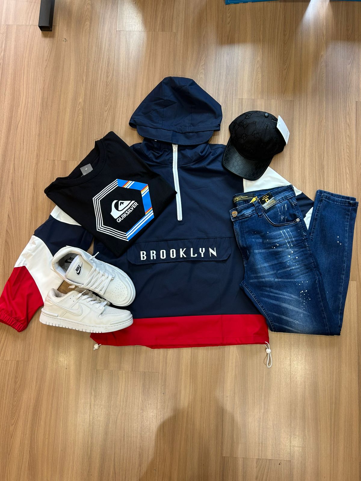 Kit com corta-vento azul, camiseta preta, jeans azul, boné e tênis branco
